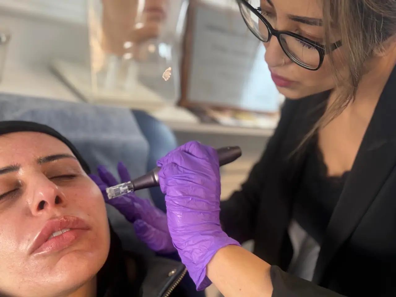 A practitioner in glasses and purple gloves carrying out a microneedling treatment on a client in the Glow By Yaz treatment room