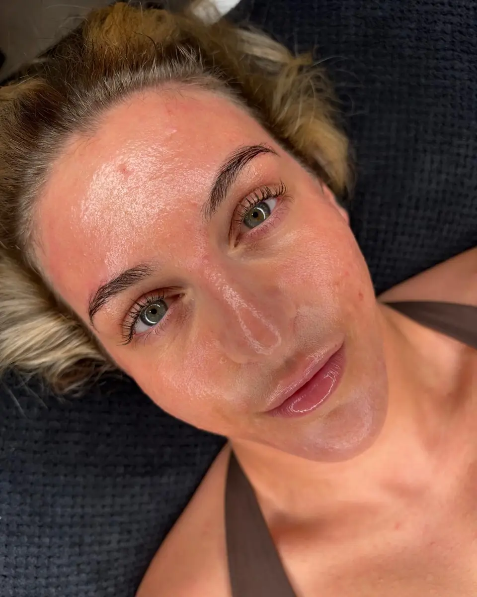 A client lying back on a dark towel in the Glow By Yaz treatment room after a facial treatment